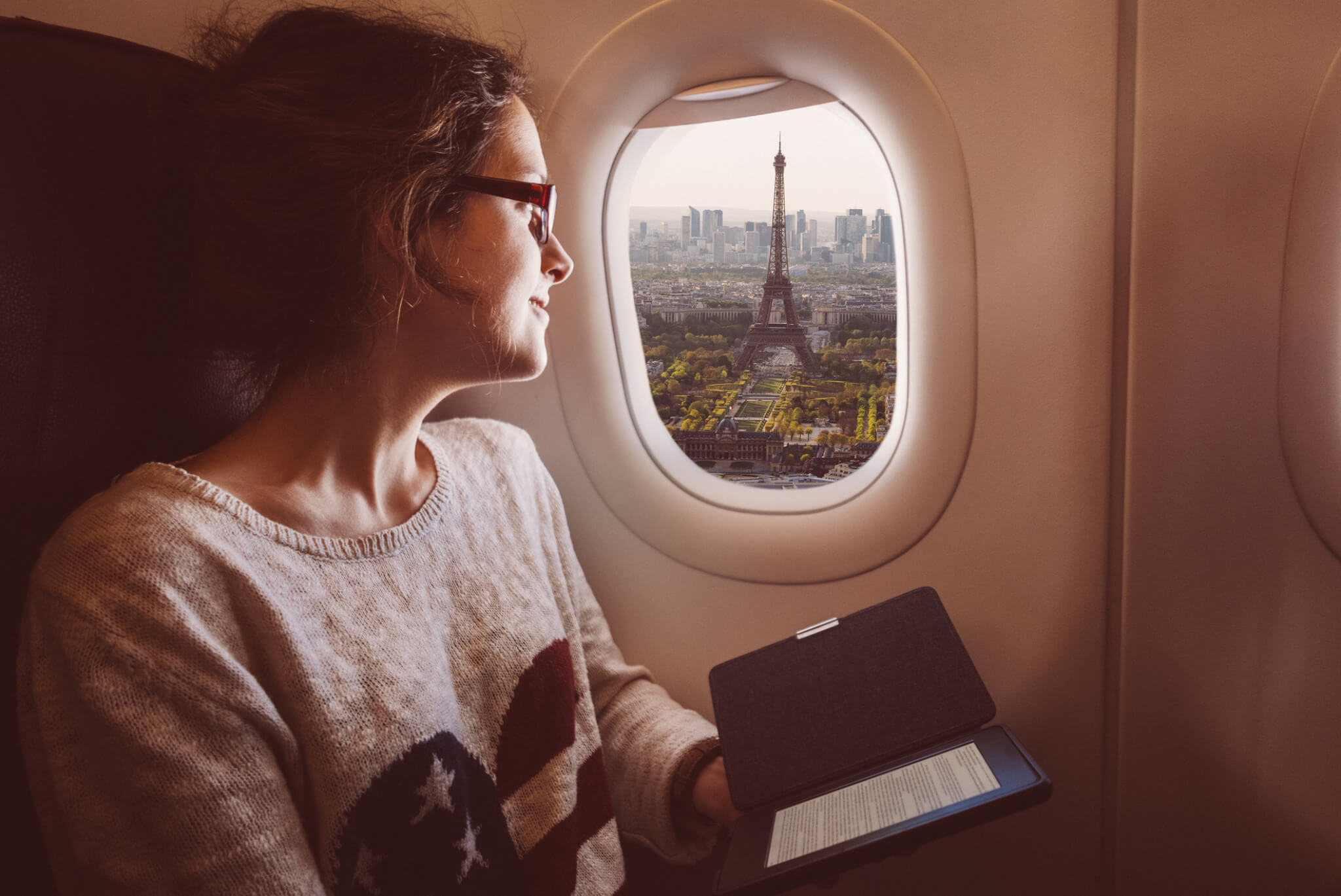 Femme souriante appréciant Paris depuis la fenêtre de l'avion