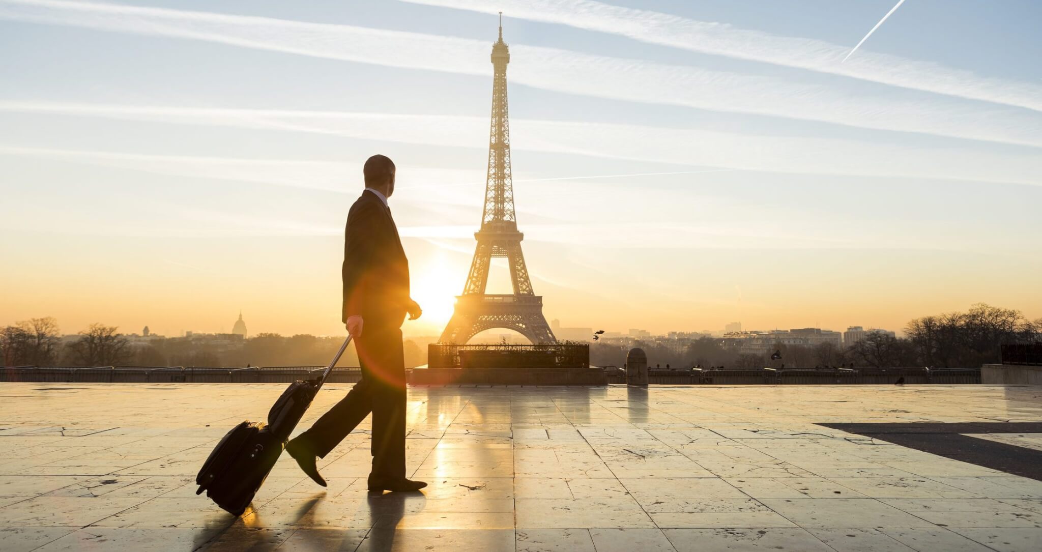 Homme avec valise devant la tour Eiffel